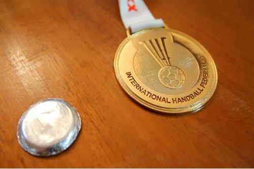 A improvisada "medalha" de prata oferecida às jogadoras antes da final contra a Sérvia e a medalha de ouro conquistada no Mundial: símbolos de uma história de sucesso da Seleção Brasileira feminina de handebol / Foto: Paulino Menezes