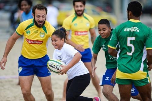 Jogadores da seleção brasileira de rugby sevens fazem um aquecimento com crianças durante a inauguração da quadra do esporte na Praia de Copacabana / Foto: Alex Ferro / Comitê Rio 2016